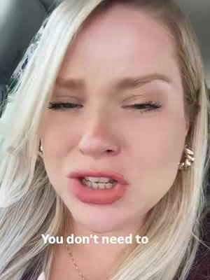 A close-up shot of a fair-skinned woman with long blonde hair and a slight squint. The woman appears to be speaking with her mouth slightly open, showing a glimpse of her teeth. The text overlayed reads "You don’t need to". The background is out-of-focus, suggesting the shot was taken in a car or interior setting.