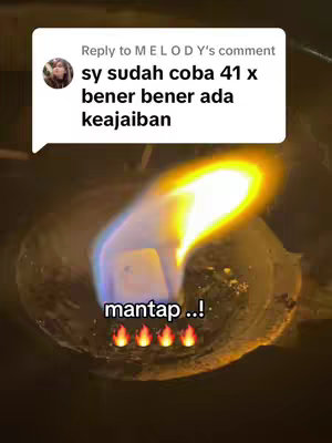 The image displays a bubbling liquid with flames rising from it, set against a dark background. A text overlay, enclosed in a white speech bubble representing a comment, is at the image's top-left. The bottom area of the image features the word "mantap" (likely meaning awesome) in white text, accompanied by four flame emojis.