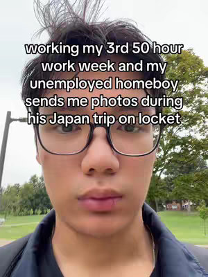 A close-up shot of a young man with dark hair and glasses, looking directly at the camera. He is wearing a dark-colored shirt and a backpack is visible on his shoulder. The background shows a green lawn and trees under a cloudy sky. Text overlay is present on the image.