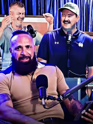 The image is a promotional shot for a podcast, featuring three men in a room with blue curtains in the background and microphones in front of them. The man in the foreground is bald and bearded, wearing a tan polo shirt, and has tattoos on his arm. The man in the upper right corner is wearing a baseball cap and a dark blue shirt. The man to the left of him is looking upwards with his hand close to his face and grinning. The lighting seems to be bright and artificial.