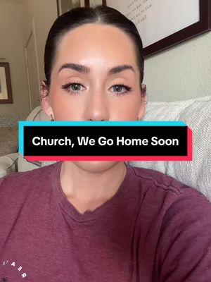 A selfie-style shot of a young woman from the chest up, framed with a blurred background. She has light skin, dark hair pulled back, and is looking directly at the camera. The hook text, in a rectangular box, covers her mouth. She wears makeup, including visible eyeshadow and earrings, and a maroon top. The background includes a glimpse of a wall and what appears to be a painting.