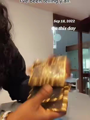 A person holding and shuffling a deck of gold-colored tarot cards. The person wearing a black shirt with long and curly dark hair and is holding the cards in their hands. Text overlay is added to the top and right-hand side of the image.