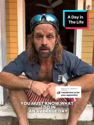 A man with a beard, sunglasses on his head, and casual clothing is sitting outside of a door. Text overlays are present, and a comment from the viewer. The background has a yellow wall