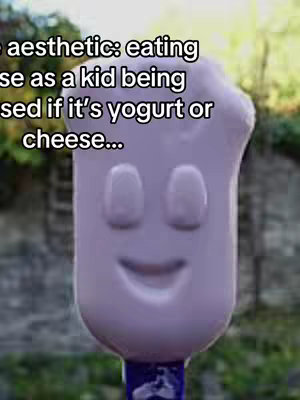 The image features a cartoon-like shape resembling a bottle of yogurt or cheese. It has a light purple color, with two oval-shaped eyes and a smiling mouth. The background blurs into green and brown tones, suggesting an outdoor setting. At the bottom, a dark blue piece is visible.