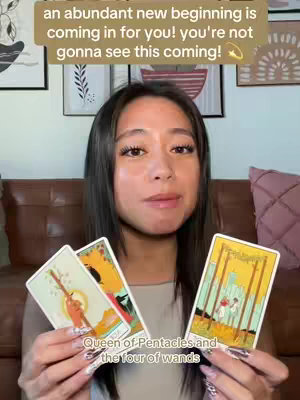 A woman with dark hair and fair skin is the central focus of the image. She holds three tarot cards, two in her left hand and one in her right. Above her, a text overlay reads an empowering message. The background has a blurred out setting, with framed artwork is visible.