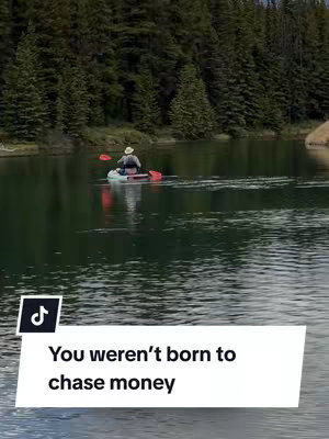 A serene landscape featuring a calm lake reflecting lush green trees. A person in a kayak paddles on the water, with a white text overlay at the bottom.