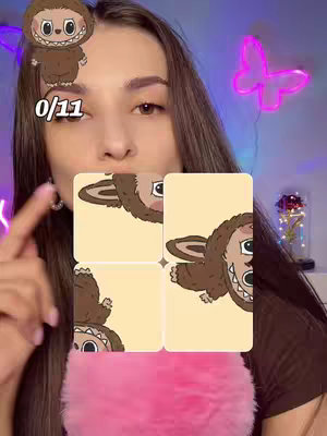 A young woman is centered in the frame, with a light pink fluffy microphone or prop in front of her. Overlayed are several cartoon images of a creature with buck teeth, set against solid tan backgrounds. The woman's hair is long and brown. Decorative elements include a neon pink butterfly and the number '0/11.'