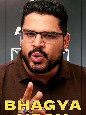 The image features a medium shot of a man with a beard and glasses looking directly at the camera with his lips pursed as if he is about to kiss. The bottom of the frame shows overlaid text in a yellow color with the words "BHAGYA UDAY" in a bold font. The background seems to be a gradient of gray and black.