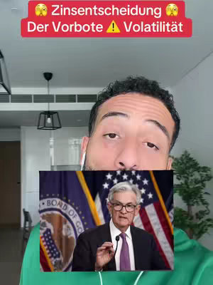 A man in a green hoodie is filming a video. The main subject of the video is a picture of Jerome Powell. There is text overlayed onto the video.