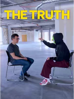 Two men sit facing each other in an empty, unfinished-looking room. One is wearing glasses and the other a black hoodie with a green mask. Overhead, large metal pipes and exposed infrastructure are visible. The words 'THE TRUTH' are displayed in large, yellow letters above the figures.