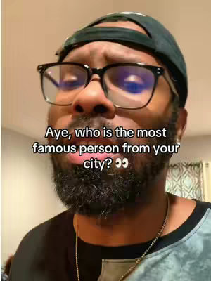 A man with a beard, glasses, and a cap is looking at the camera and talking. Text overlay says 'Aye, who is the most famous person from your city?'