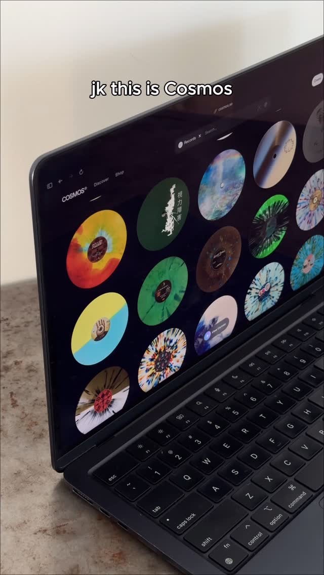A laptop is open, displaying a website or app interface with a grid of colorful circular graphics. The screen is angled towards the viewer.
