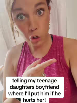 A woman with a surprised expression is pointing her finger as if speaking. She has light skin, short dark hair, and is wearing a pink tank top. A text overlay at the bottom says, "telling my teenage daughters boyfriend where I'll put him if he hurts her!"