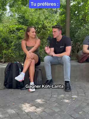 A man and a woman are sitting on a low wall with a lush green background. The man is holding a microphone. The woman is looking at the man. Text overlays include "Tu préfères" in a blue box and 'Gagner Koh-Lanta' at the bottom.
