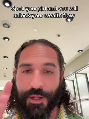 A selfie-style shot featuring a man with a long, dark beard and hair, wearing a green and yellow knitted top. He's positioned in front of a neutral background, likely a store interior or shop. Above, there's overlaid text in a simple sans-serif font.