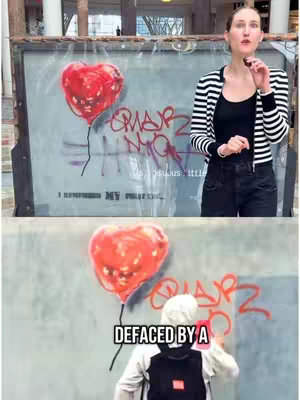 The cover image is split into two parts. On the top half, a woman stands in front of a wall with a graffitied heart balloon and text. She wears a black and white striped jacket, a black top, black shorts and has her hair pulled back. The bottom half shows another image of the heart balloon with the words 'DEFACED BY A' overlaid with a person in the scene. The woman is on the right. The graffiti art is a heart-shaped balloon.