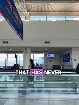 The image shows an airport scene. The background is a light-filled terminal with high ceilings and large windows. A moving walkway is in the foreground, its transparent surface reflecting the overall brightness of the scene. A person with long black hair stands on the walkway. The text overlay 'THAT HAS NEVER' is positioned at the center.