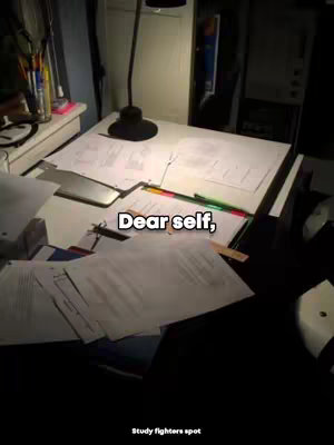 The image shows a well-lit desk covered in papers and drawing materials. A desk lamp is positioned above the papers.