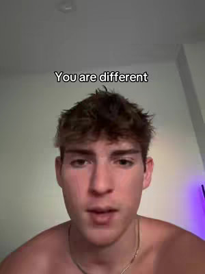 A young man looks directly at the camera, framed from the chest up. He has short, tousled brown hair and light skin. He is shirtless, and a gold chain is visible around his neck. The text overlay 'You are different' appears above his head in a standard, sans-serif font. The background appears to be a plain wall.