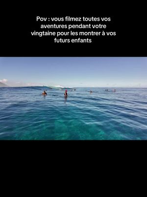 An eye-level shot captures the expansive view of a blue ocean under a clear sky with a few people in the water. The text overlay at the top of the image reads 'Pov : vous filmez toutes vos aventures pendant votre vingtaine pour les montrer à vos futurs enfants'.