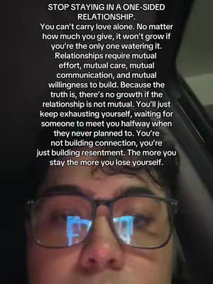 A selfie-style image featuring an individual wearing glasses with text overlayed. The person is positioned from the chest up, filling most of the frame. The background has muted tones, suggesting a neutral or indoor setting.