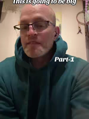 A middle-aged man with glasses and a shaved head wearing a teal hoodie. He is looking at the camera. There is text on the top, and in the bottom right that overlaps the man.