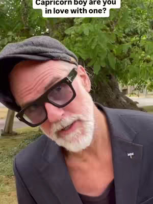 A medium shot features a man looking towards the camera, slightly angled. He wears glasses and a cap, with a trimmed beard. The setting appears to be outdoors, with a green leafy background.