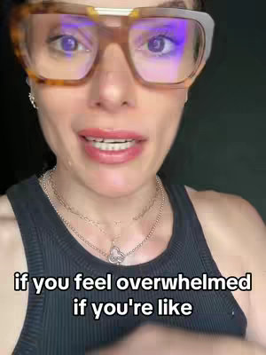 A close-up shot of a woman's face, with emphasis on her eyes behind large framed glasses. Beneath her is a black tank top and silver necklaces. Text overlayed on the image.