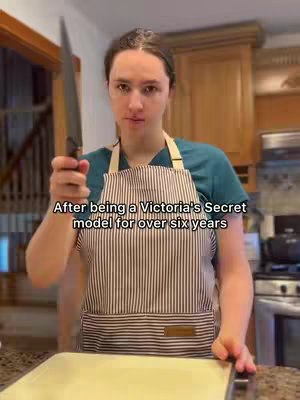 A person in an apron and holding a knife in a kitchen setting. The background shows wooden cabinets and a countertop. Text overlay reads, 'After being a Victoria's Secret model for over six years'.