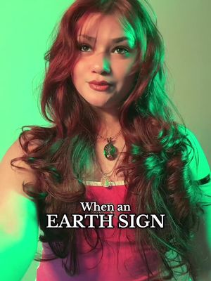 The cover image features a young woman with long, wavy red hair, lit with green and yellow lighting. Text overlays across the image. The foreground showcases the woman looking directly at the viewer. She is wearing a pink top. The background is a gradient of green and yellow.