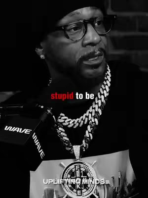A black and white close-up of a man wearing glasses, a beanie, and a jeweled necklace. Text overlayed in red reads 'stupid to be'. The man is looking slightly to the side.
