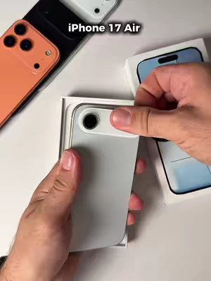 The cover image shows hands holding a new, light gray iPhone 17 Air, partially removed from its box. Other iPhone boxes and phones (orange and white) are visible in the background on a white surface.