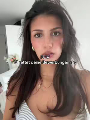 A woman with long dark hair looks directly at the camera. The overlay text reads \"POV KI rettet deine Bewerbungen >>>\" (POV AI saves your applications >>>). The background is a softly lit room with a glimpse of a white wardrobe and a vase of flowers.