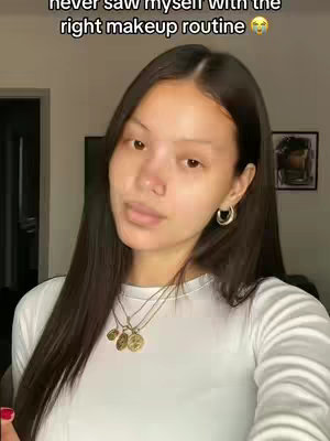 A woman with long dark hair in a white top is looking at the camera. She has minimal makeup on. Text overlays the top.