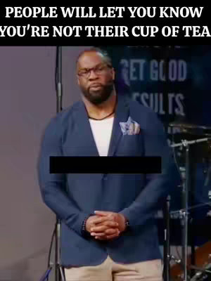 A man wearing glasses, a blue blazer, and a white shirt stands in front of a blurred background. The image has text overlays at the top and a black rectangle covering a portion of the man's torso. The man is facing the viewer with his hands clasped in front of him.