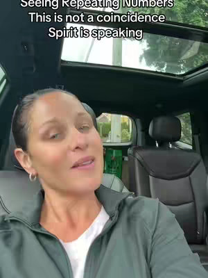 A woman is seated inside a car. She’s looking towards the camera and talking. Above her is a graphic with overlapping text in a sans-serif font, and the car's interior can be seen along with greenery visible through the car windows.
