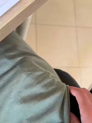An overhead shot shows a person, only their upper body is visible. They wear a green shirt, with part of their arm visible, and a part of a table is shown on the top of the image with a tan tiled floor on the right.