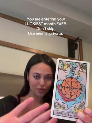 A woman with dark hair holds a tarot card, the "Wheel of Fortune" card, in front of her. Text overlays the main image, reading, "You are entering your LUCKIEST month EVER. Don't skip. Use even in private."
