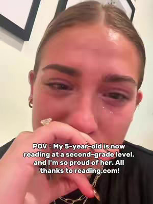 The cover image is a close-up shot of a young woman's face. She appears to be crying, with visible tears and a distressed expression. Her right hand is raised towards her face, partially covering her mouth. Her left hand is holding a ring and necklace. The background is blurred, but part of a wall frame is visible. The colors are muted, emphasizing the emotional tone.