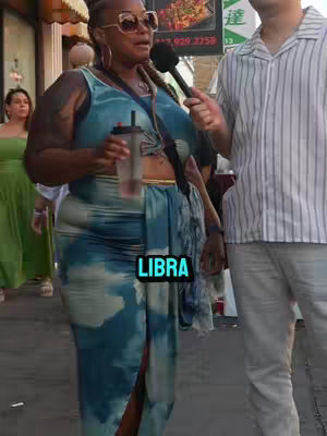 A woman wearing sunglasses and a colorful dress is being interviewed with a microphone. The text "LIBRA" is overlaid on the image.