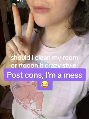 A person is shown from the chest up, giving a peace sign with two fingers, their lips are slightly apart. A banner on the image says "should I clean my room or #goon it crazy style, Post cons, I'm a mess", also has a yellow laughing emoji in the lower part.