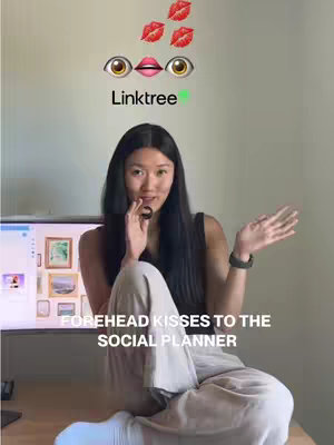 A woman with long, dark hair sits casually on a wooden desk, gesturing with her right hand and holding a finger to her lips with her left. Above her are emoji eyes looking at a mouth, topped by three red lips. The word 'Linktree', in a green font, sits beneath the eyes and lips. Text at the bottom of the image reads, 'FOREHEAD KISSES TO THE SOCIAL PLANNER,' in a white font.
