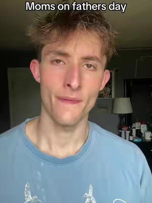 A young man with light skin and light brown hair is the central focus, positioned against a blurred background. He's wearing a light blue t-shirt. The image has a neutral color palette with soft lighting.