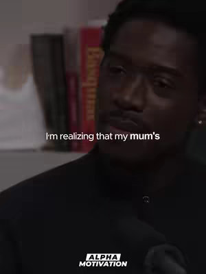 A medium shot of Damson Idris with a quote overlayed. Idris, a Black man with short hair, is seen from the chest up, facing slightly to the right. The background includes blurry bookshelves. The text overlay is white, positioned above Idris and partially obscures his face. Below the text is the Alpha Motivation logo in a white box, centered. The lighting is soft, and the overall tone is serious.