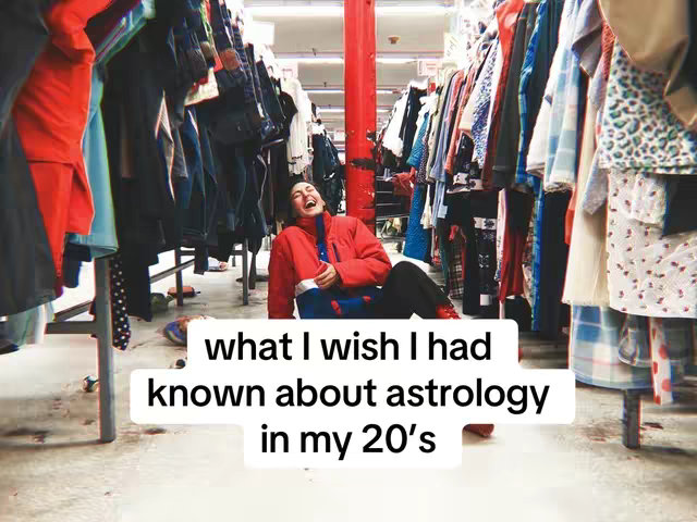 A person in a red jacket laughs, surrounded by racks of clothing in an apparent thrift store or vintage shop. The background includes more racks of clothes, creating a cluttered but visually interesting setting. The image is well-lit and has a warm tone. Text overlay adds context about astrology.