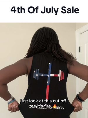 A person from the back wearing a black sleeveless top with a colorful design is shown, displaying the clothing article. Above the individual, there's an upper-case text that that says '4th Of July Sale'. The text 'just look at this cut off tee, it's fire' is placed at the bottom of the image.