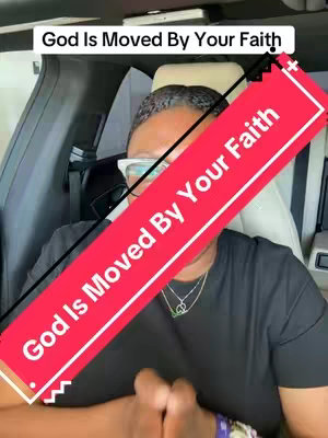 A person, likely in a car, is the primary subject. The individual is wearing glasses and a black shirt. A red, angled banner containing white text that reads "God Is Moved By Your Faith" overlays the image.