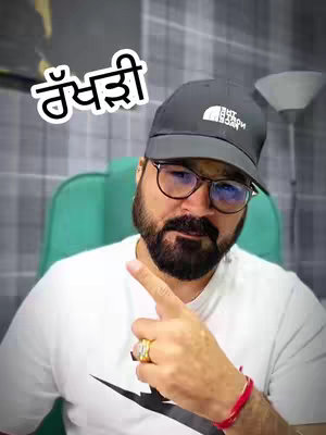 A man with a beard and glasses points to his right with his index finger. He wears a black cap with a white logo, a white t-shirt, and a gold ring. Text in an oval bubble with a white outline and script is in the top-left corner.