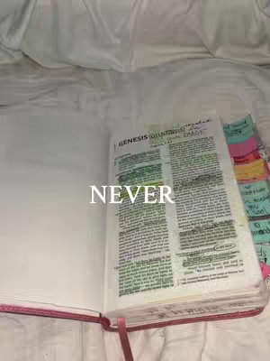 An open book, presumably a Bible, lies on a bed of white. The book is open to a marked page, the text annotated with highlighter, and sticky notes. The word 'NEVER' is overlaid on the book's text.