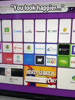 Screenshot of a computer screen displaying various application icons, with a text overlay at the top. The screen is angled, showing a purple background with various app icons arranged in a grid. A search box is visible with 'Hero Search Pow!' in a comic-style bubble at the bottom.